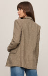 Woman wearing a brown checkered coat against a plain background