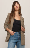 Woman wearing a plaid blazer over a black top and blue jeans on a plain background