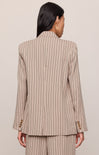 Person wearing a beige pinstripe suit against a plain background
