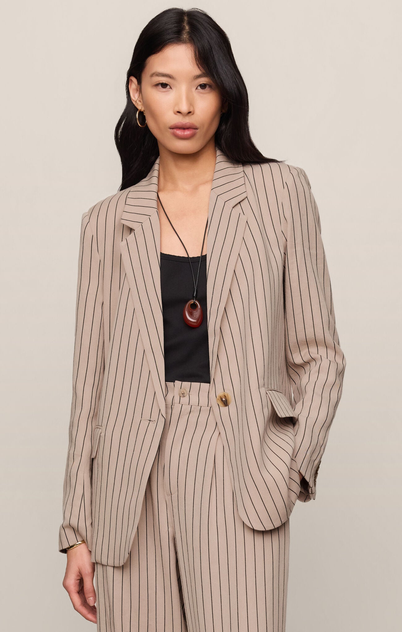 Woman wearing a beige pinstripe suit with a plain background