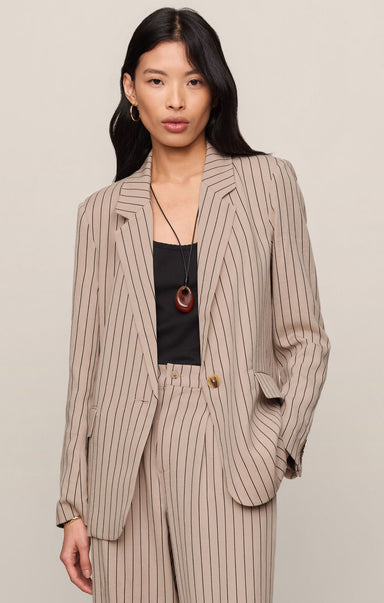 Woman wearing a beige pinstripe suit with a plain background