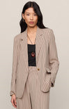 Woman wearing a beige pinstripe suit with a plain background
