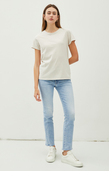 Woman wearing a plain white t-shirt and light blue jeans on a white background