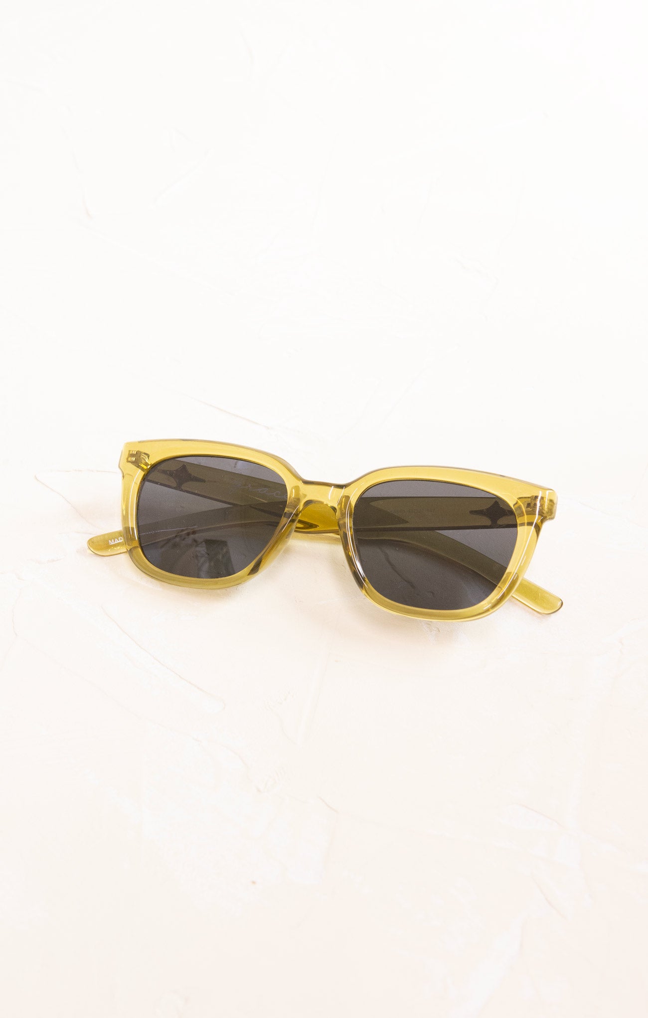 Gold-framed sunglasses with dark lenses on a white background