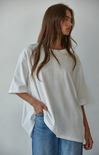 Woman wearing an oversized white t-shirt and blue jeans against a plain background