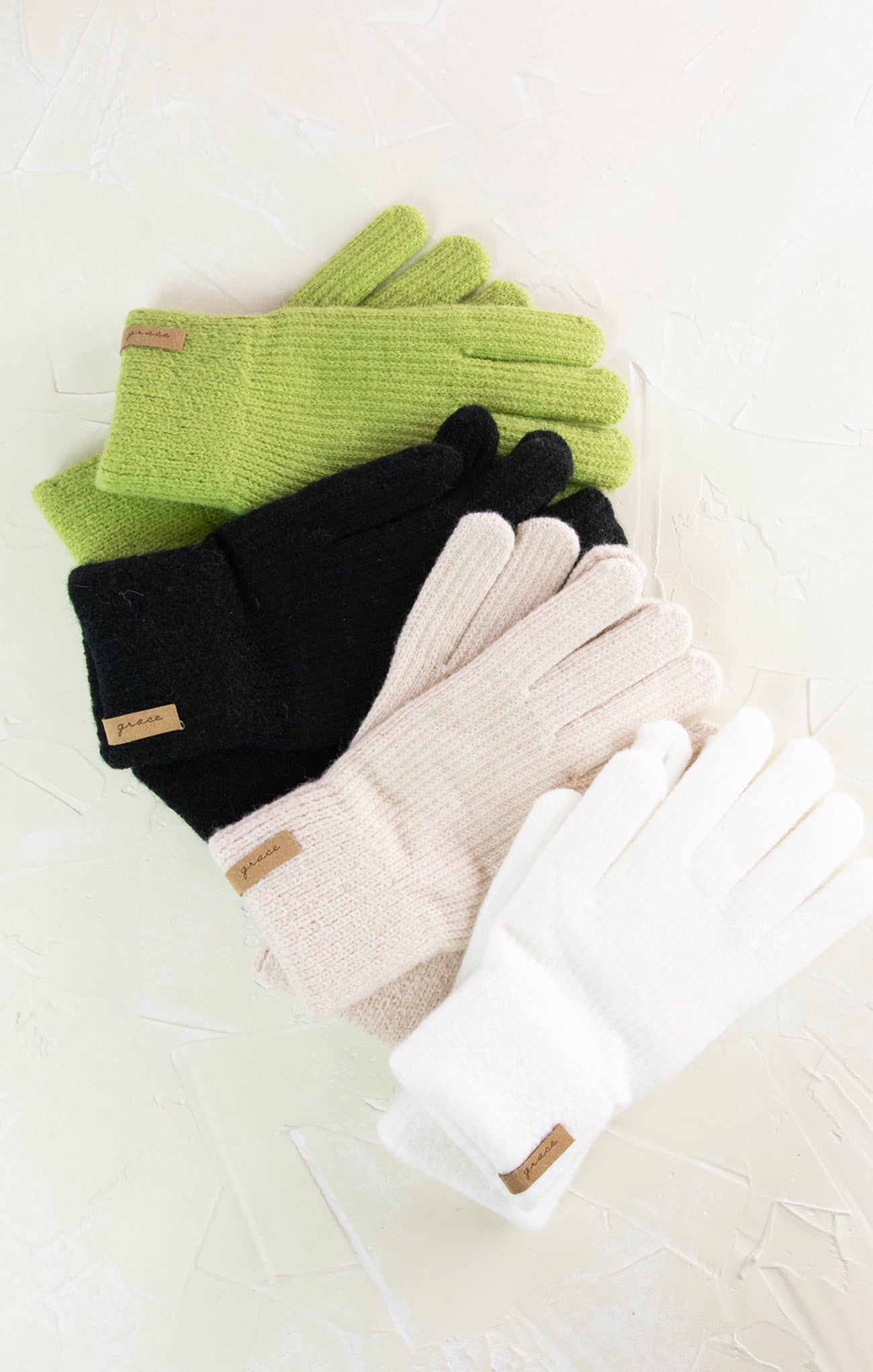 Set of green, black, beige, and white gloves on a light background