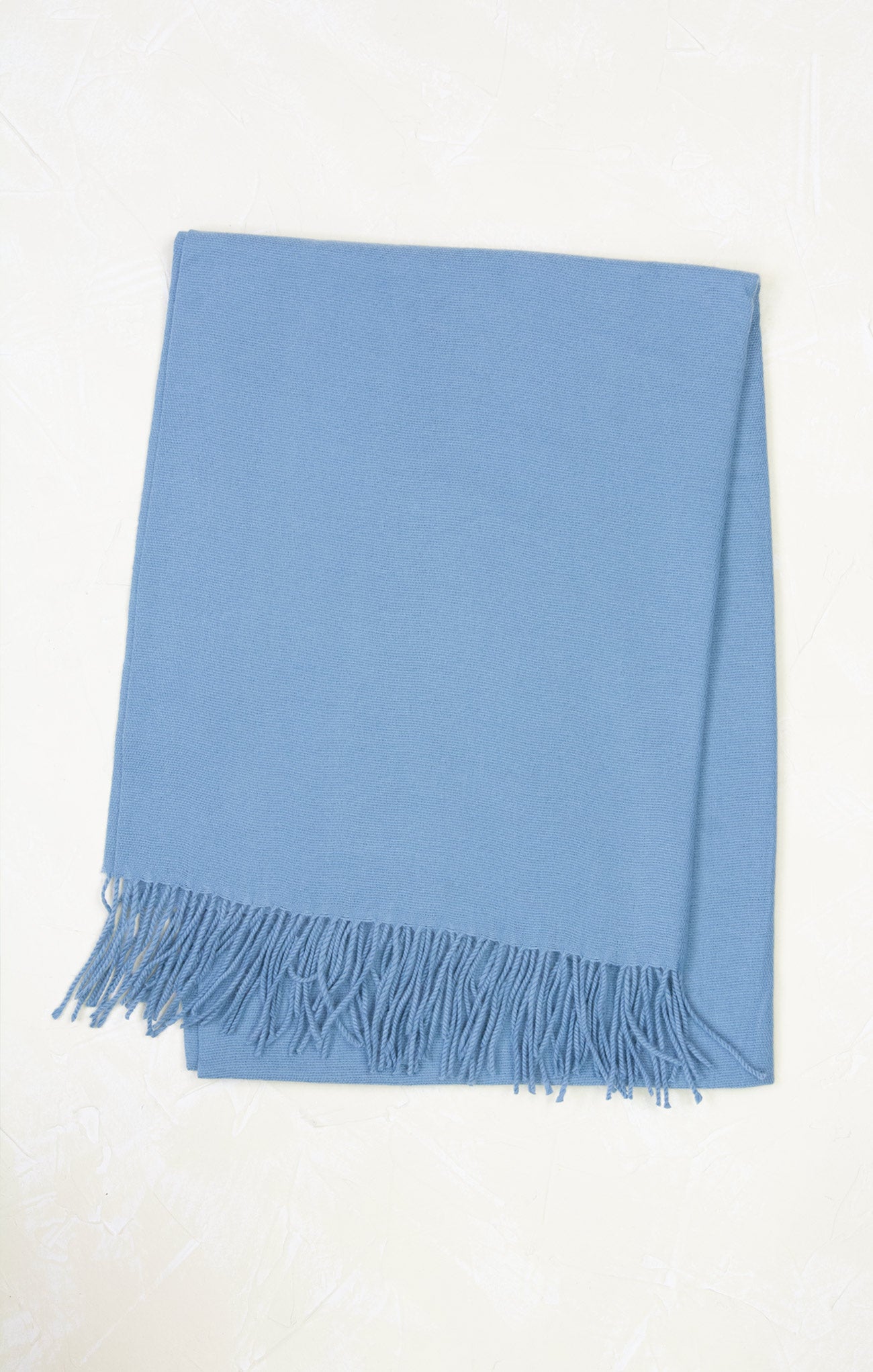 Light blue throw blanket with fringes on a white background