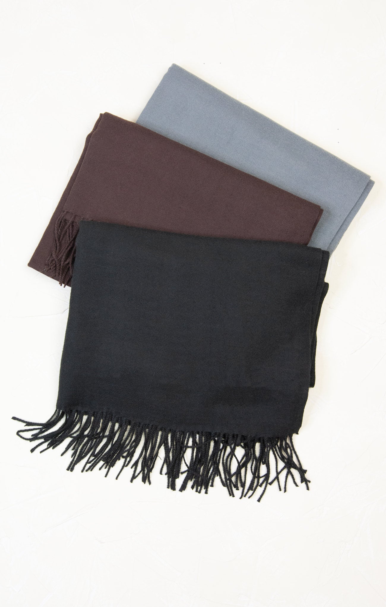 Three scarves in black, brown, and gray on a white background