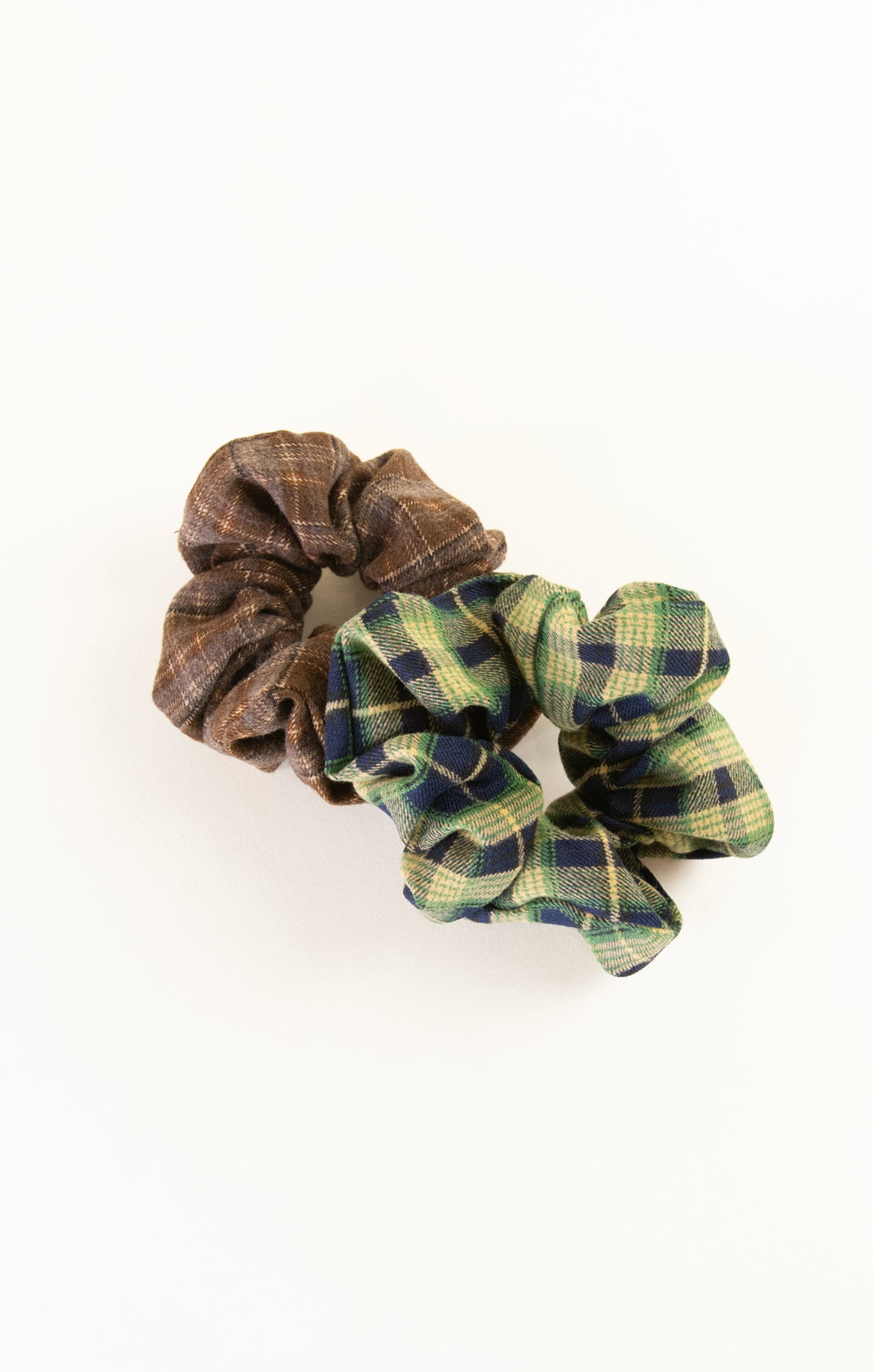 Two plaid scrunchies, one brown and one green and blue, on a white background.