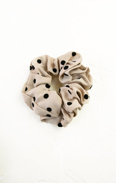 Beige scrunchie with black polka dots on a white background