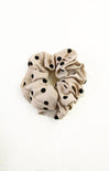 Beige scrunchie with black polka dots on a white background