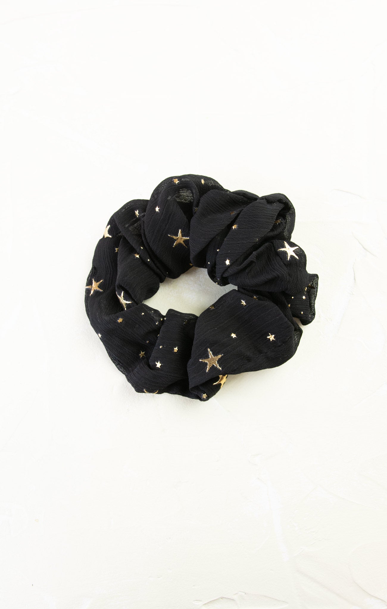 Black scrunchie with gold stars on a white background