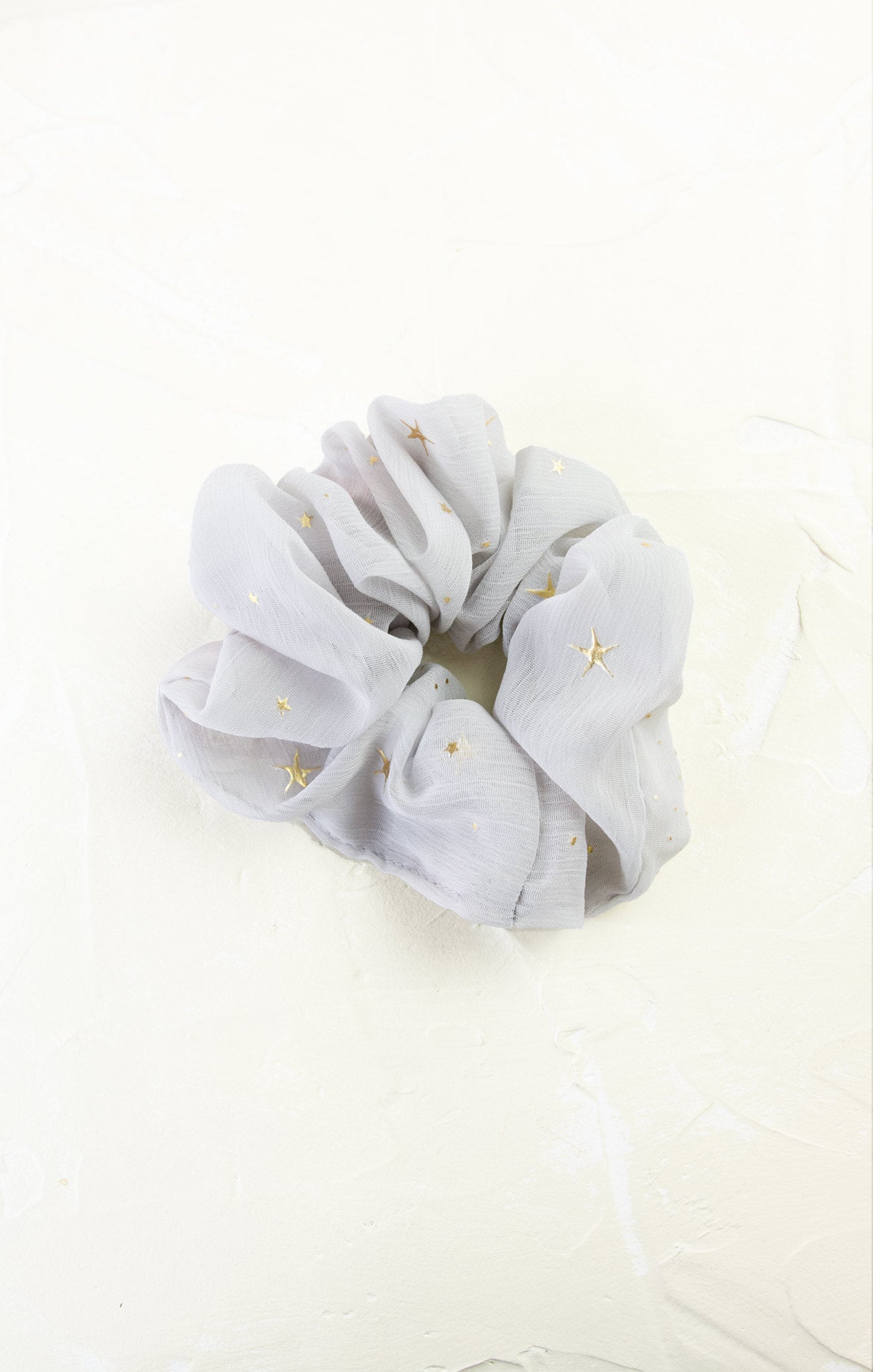 Gray scrunchie with gold stars on a white background