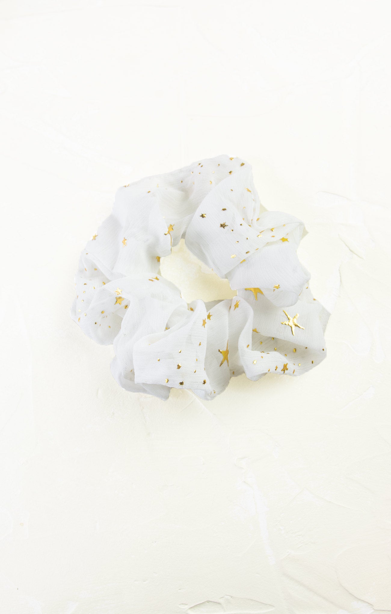 White scrunchie with gold stars on a white background