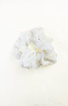 White scrunchie with gold stars on a white background