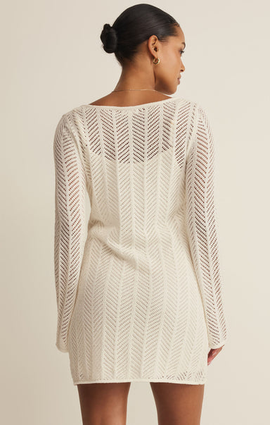 Woman wearing a beige knitted dress against a plain background