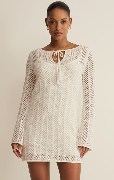 Woman wearing a white lace dress against a beige background
