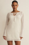 Woman wearing a white lace dress against a beige background