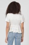 Person wearing a white ruffled blouse and blue jeans on a plain background