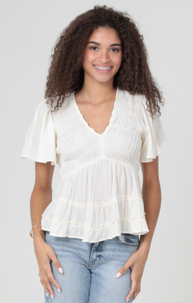 Woman wearing a white blouse and blue jeans against a plain background