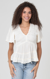 Woman wearing a white blouse and blue jeans against a plain background