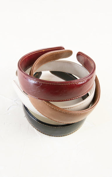 Stack of leather belts in various colors on a white background