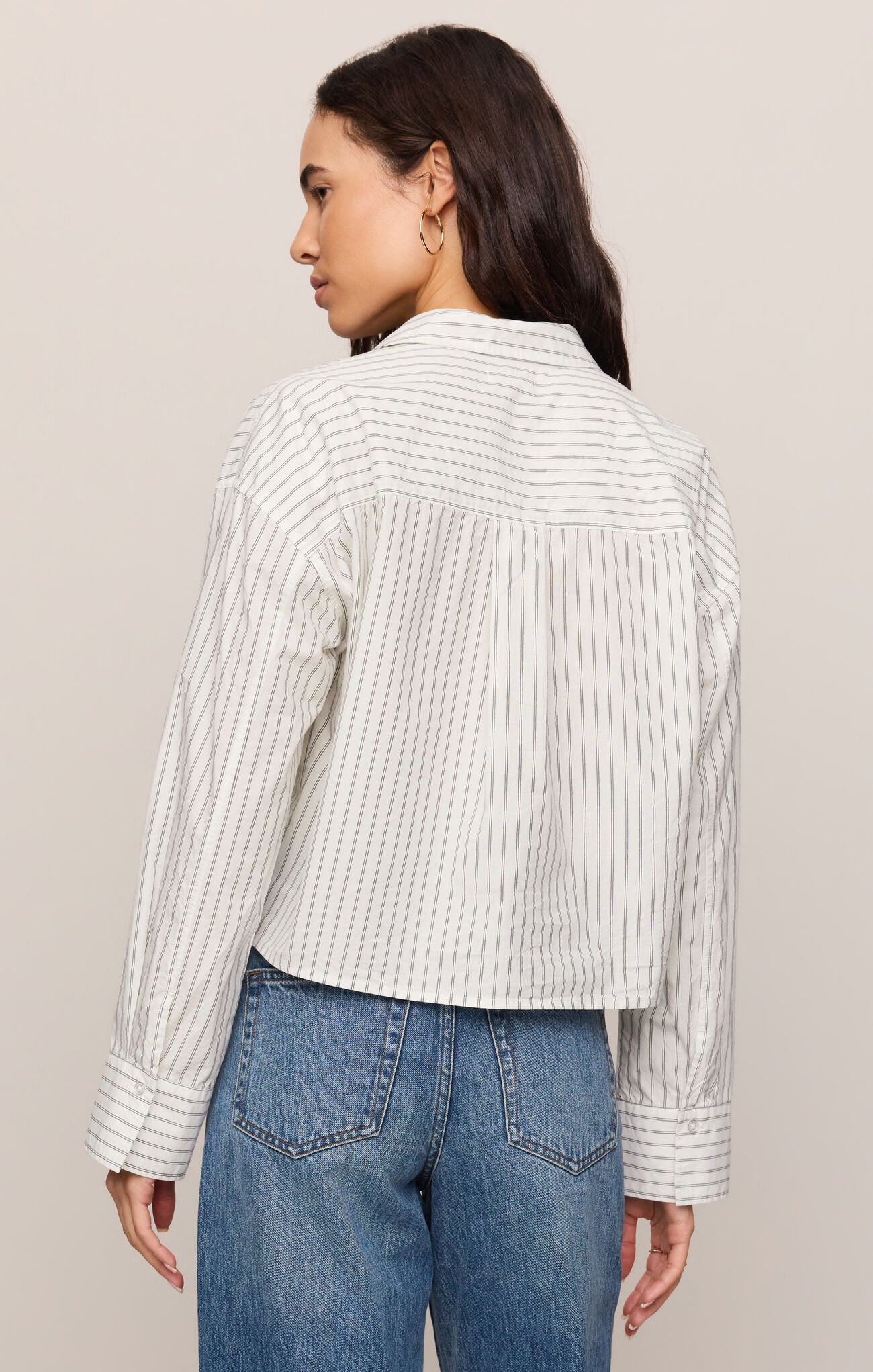 Person wearing a striped shirt and jeans against a plain background