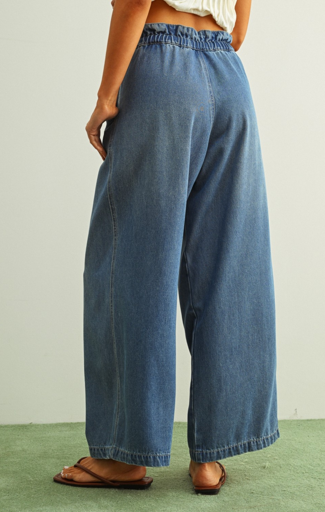 Person wearing blue wide-leg jeans on a plain background