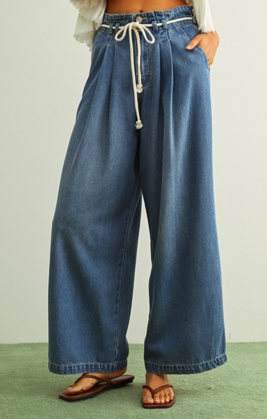 Wide-leg blue jeans with a drawstring waist on a plain background