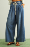 Wide-leg blue jeans with a drawstring waist on a plain background
