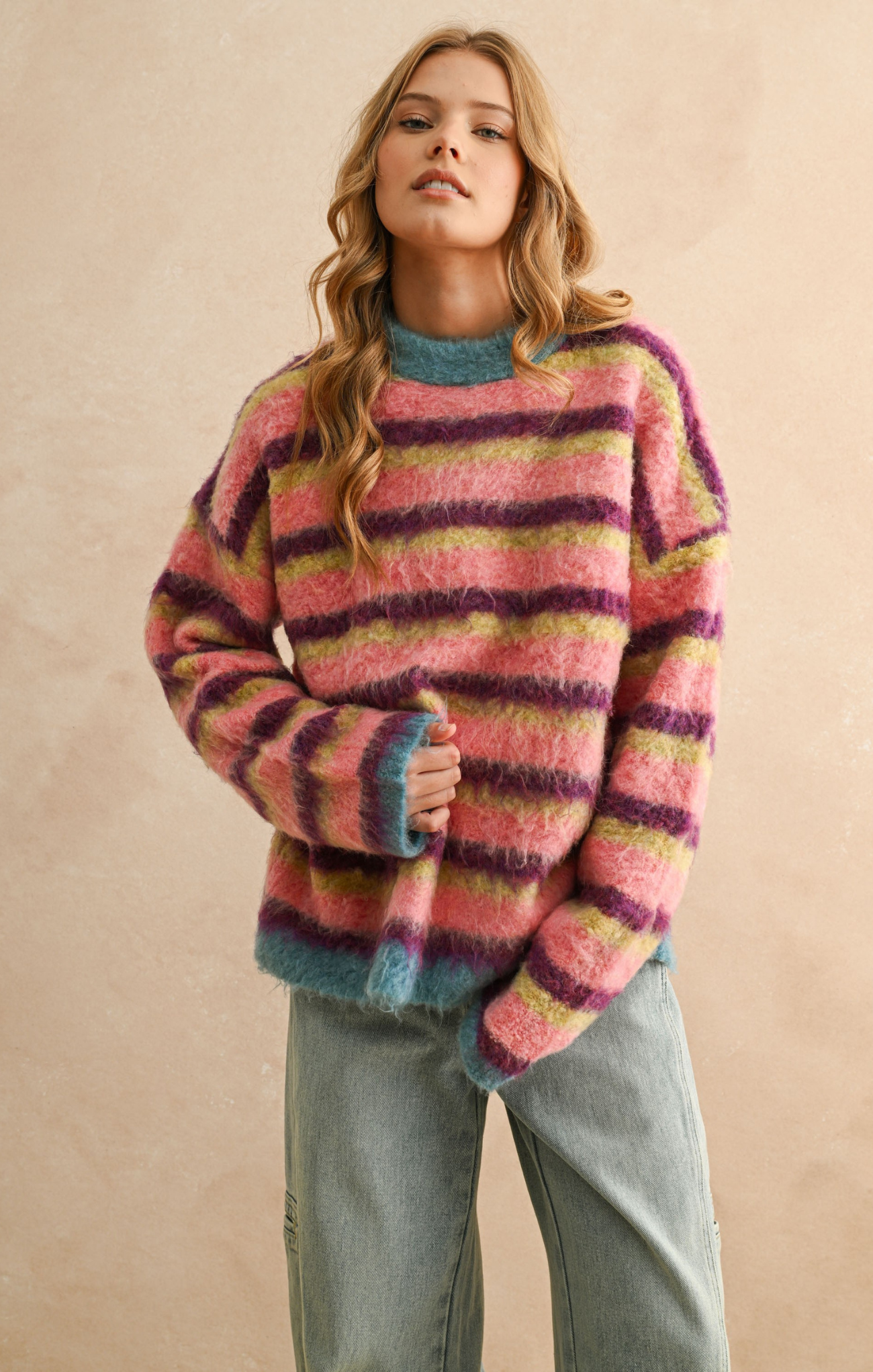 Woman wearing a colorful striped sweater against a beige background