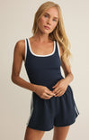 Woman wearing a navy blue tank top and shorts with white trim on a beige background