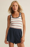 Woman wearing a striped tank top and navy shorts on a beige background