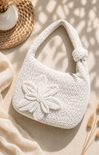 White textured handbag with floral detail on a beige surface