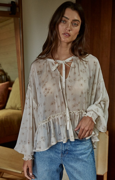 Woman wearing a floral blouse and blue jeans indoors