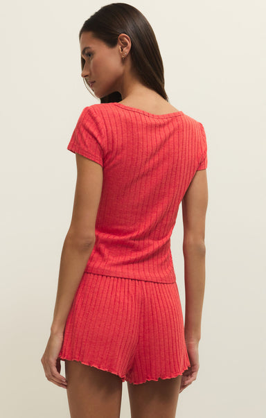 Woman wearing a red ribbed outfit on a beige background