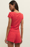 Woman wearing a red ribbed outfit on a beige background