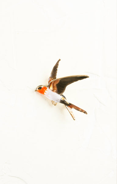 Metallic bird-shaped brooch on a white background