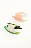 Two glass bird figurines, one pink and one green, on a white background