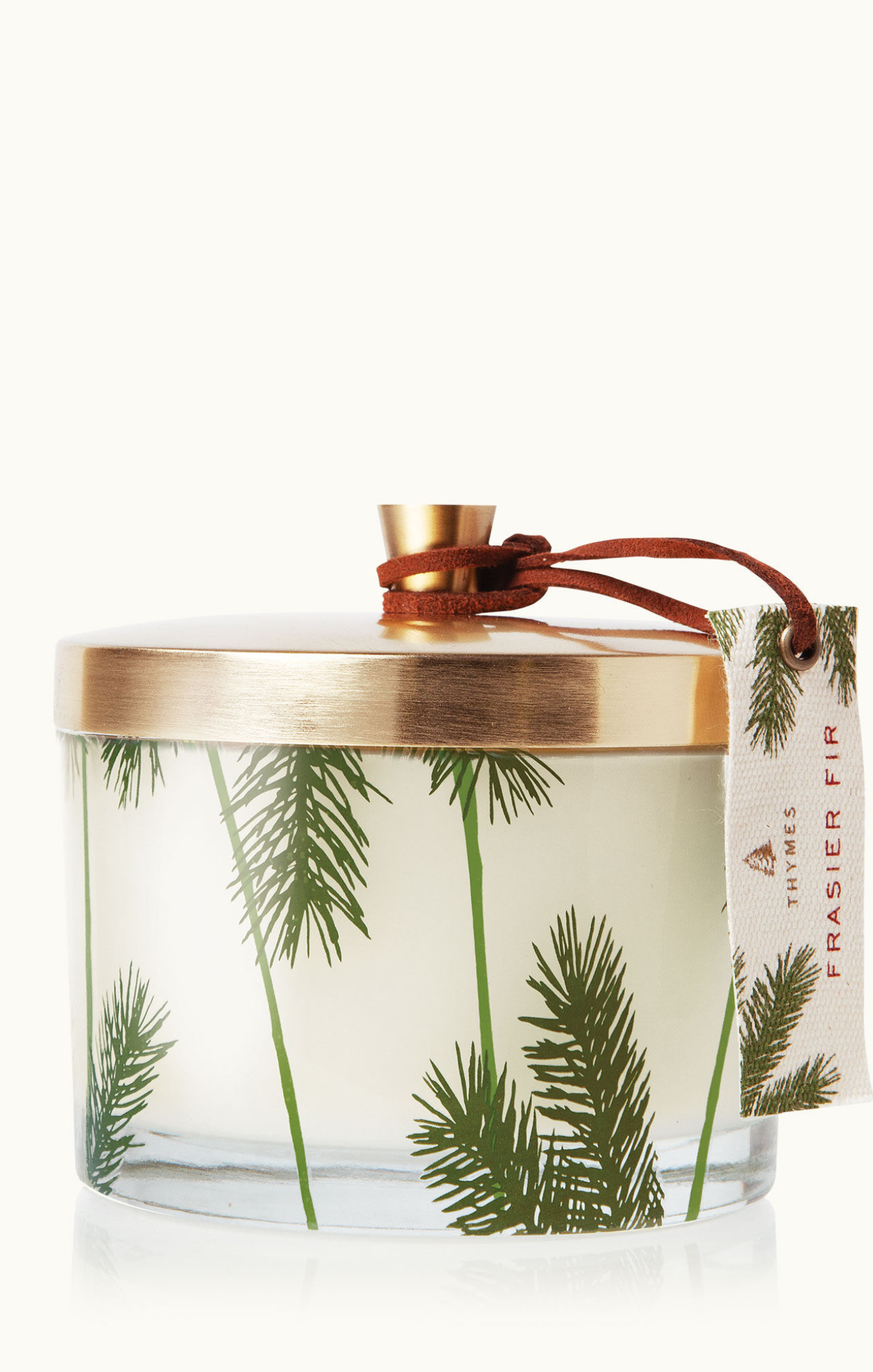 A Frasier Fir pine needle 3-wick candle in a clear glass jar with a gold lid, adorned with pine needle designs. A brown and white label is attached to the jar.