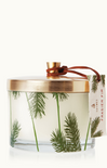 A Frasier Fir pine needle 3-wick candle in a clear glass jar with a gold lid, adorned with pine needle designs. A brown and white label is attached to the jar.