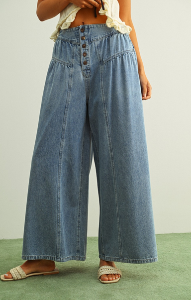 Person wearing wide-leg blue jeans on a plain background