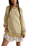 Woman wearing a yellow striped sweater with a white lace dress underneath on a white background