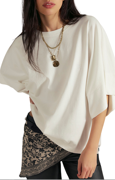 Woman wearing a white oversized top with a patterned skirt on a white background