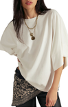 Woman wearing a white oversized top with a patterned skirt on a white background