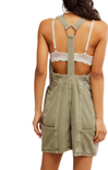 Person wearing a green overall dress with lace detailing on a white background