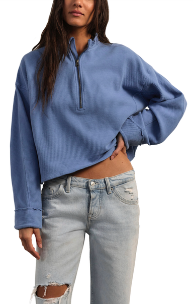 Person wearing a blue cropped sweater and light blue jeans on a white background