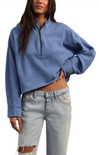 Person wearing a blue cropped sweater and light blue jeans on a white background