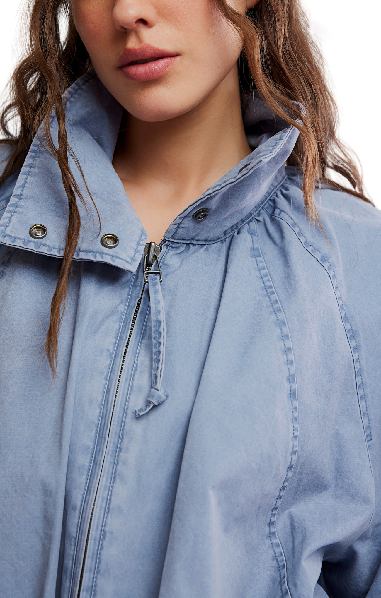 Close-up of a person wearing a light blue denim jacket with a zipper.