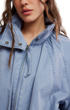Close-up of a person wearing a light blue denim jacket with a zipper.